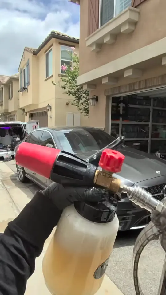 Foam cannon loaded and aimed at a dark sedan in a residential driveway