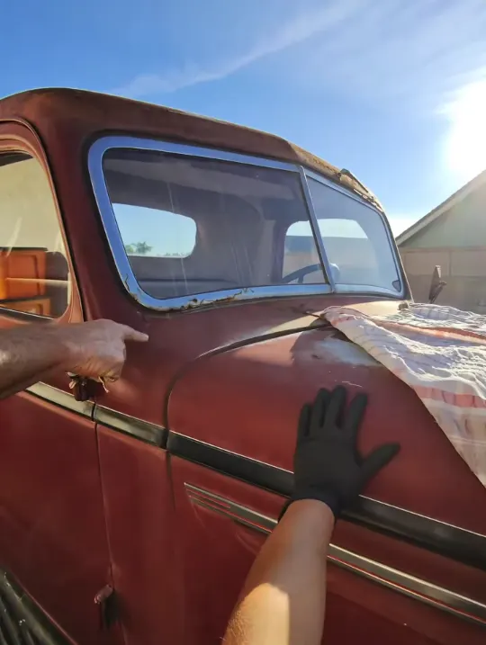 Wiping down the door of a classic red pickup truck