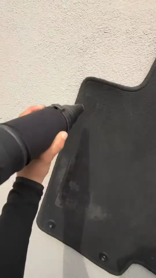 Vacuuming a carpet floor mat outside the vehicle