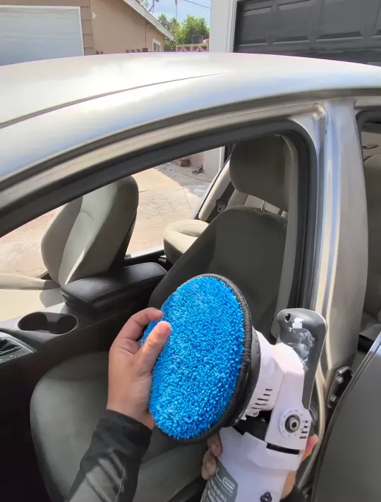 Scrubbing a cloth seat with a drill brush during an interior reset