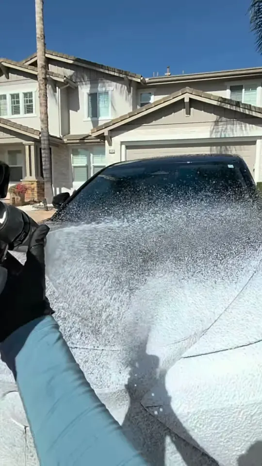 Spraying foam across a Lexus SUV in a sunny driveway