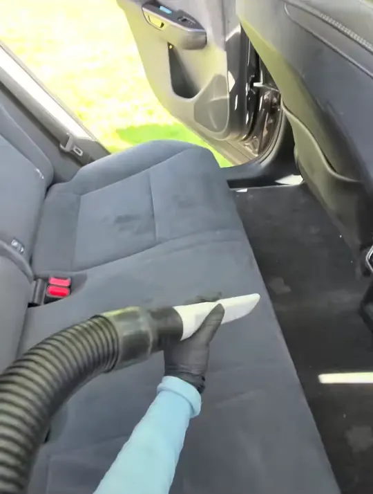 Vacuuming a fabric rear seat in a Lexus SUV