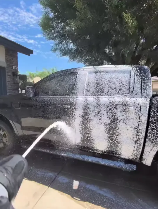 Rinsing foam off the side of a black pickup truck