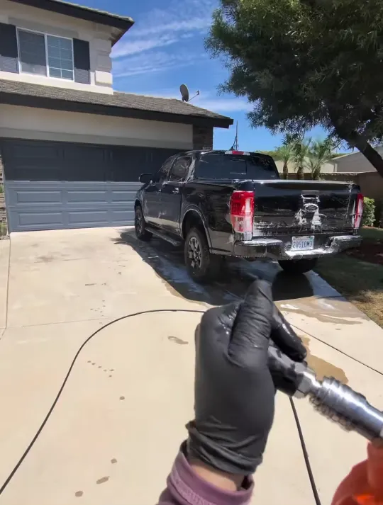 Pressure washer pre-rinse on a black Ford Ranger in a driveway