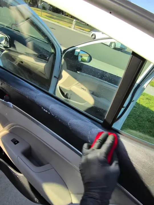 Wiping down a sedan door panel with a microfiber towel