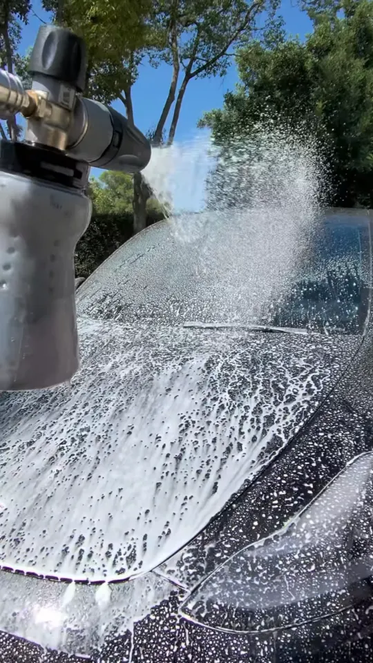 Foam and water across the hood of a black Tesla during the wash