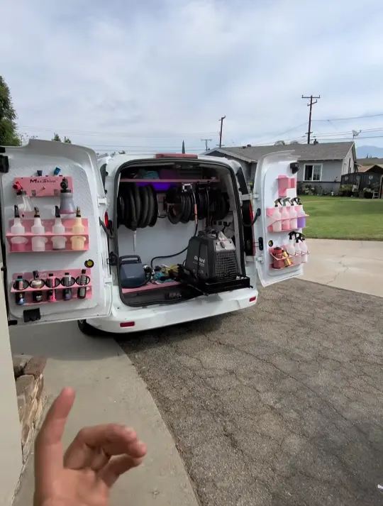 The Spotless Auto Care van with rear doors open, hose reels and product shelving inside