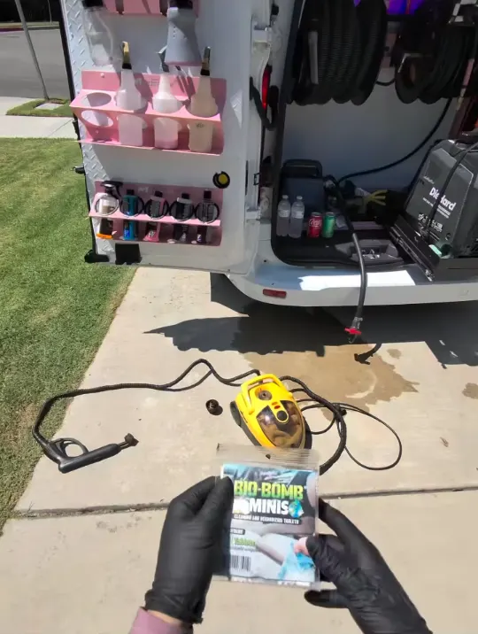 Mobile detailing setup parked on a driveway, van doors open with tools laid out